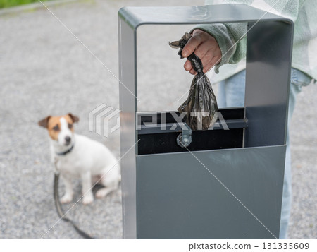 Responsible Dog Owner Disposing of Waste in Park Bin. Responsible Dog Owner Disposing of Waste in Park Bin. 131335609