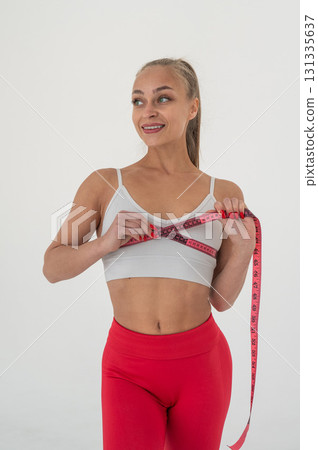 Young woman measuring her chest circumference on white background. 131335637