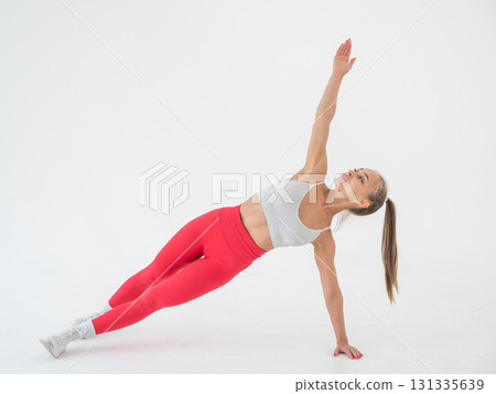 Young woman doing side plank on white background. 131335639