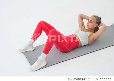 Young woman doing abdominal exercises on white background. Young woman doing abdominal exercises on white background. 131335656