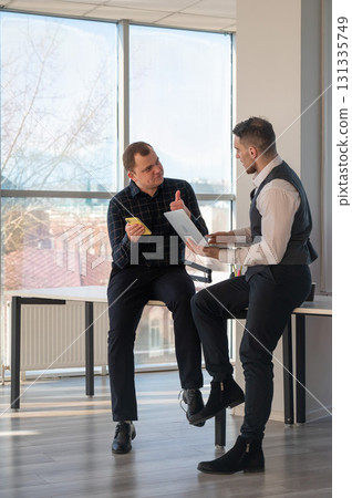 Two Caucasian men discussing work in an office. Businessman with a hearing aid.  131335749