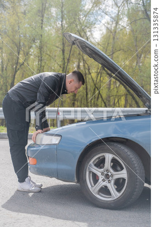 Caucasian man looking under the hood of his car.  131335874
