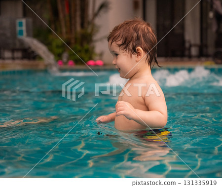 Caucasian one year old boy playing ball in swimming pool.  131335919