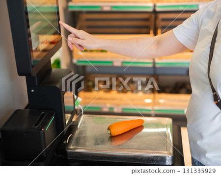 A woman weighs carrots at a self-checkout. A woman weighs carrots at a self-checkout. 131335929