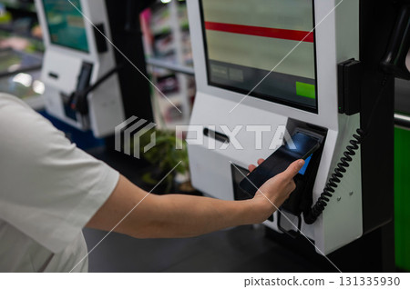 A woman pays using her smartphone at a self-checkout.  131335930
