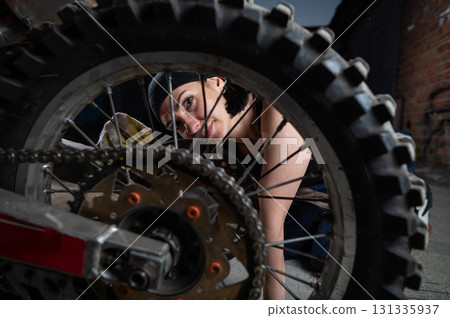 Brunette woman repairs a red motorcycle. Brunette woman repairs a red motorcycle. 131335937