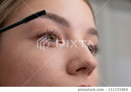 Young Woman Applying Mascara to Enhance Eyelashes. Young Woman Applying Mascara to Enhance Eyelashes. 131335968
