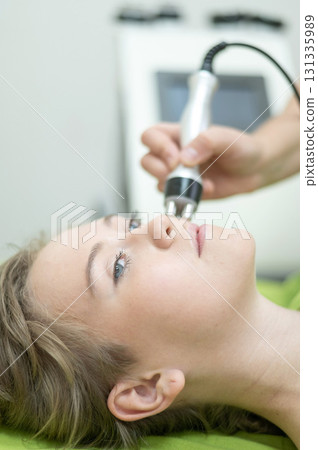 Caucasian woman undergoing radio wave RF lifting procedure in beauty salon. Caucasian woman undergoing radio wave RF lifting procedure in beauty salon. 131335989