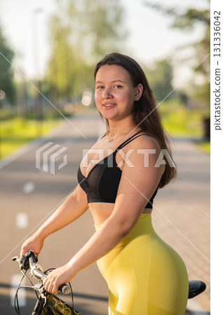 Curvy Caucasian Woman Riding Bicycle in Park.  131336042