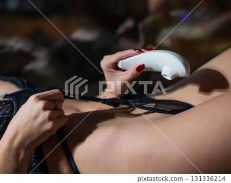 Woman using white clitoral vacuum stimulator.  131336214