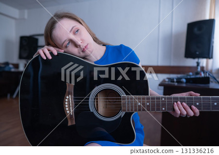 Young woman playing guitar in recording studio.  131336216