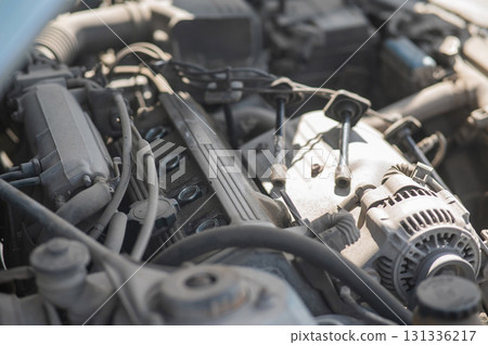 Unscrewed spark plugs under the hood of a car.  131336217