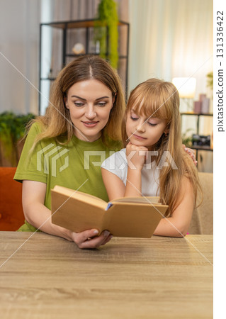 Mother daughter alternate reading aloud child book at table share story warm mood calm focus family 131336422