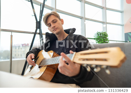 Caucasian man sitting in cafe and playing guitar.  131336429