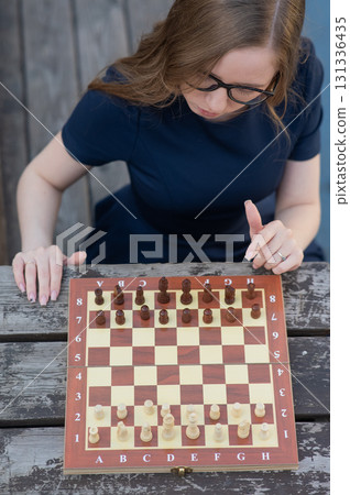 Caucasian woman playing chess outdoors.  131336435