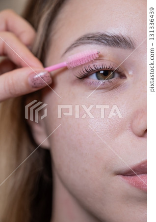 Caucasian woman brushing her eyelashes after lamination. Caucasian woman brushing her eyelashes after lamination. 131336439