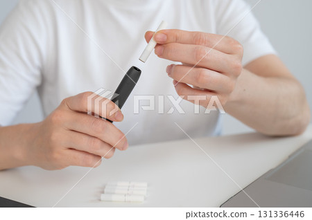 A woman inserts a cigarette stick into a tobacco heating system. Electronic cigarette. A woman inserts a cigarette stick into a tobacco heating system. Electronic cigarette. 131336446