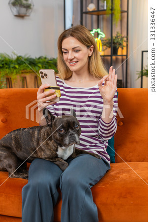 Middle-aged woman with dog orders pet food in app pays by credit card on smartphone shows OK gesture Middle-aged woman with dog orders pet food in app pays by credit card on smartphone shows OK gesture 131336447