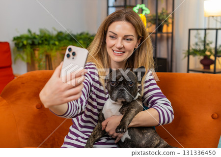 Middle-aged woman with dog makes funny selfies on smartphone laughs and joins video call conference 131336450