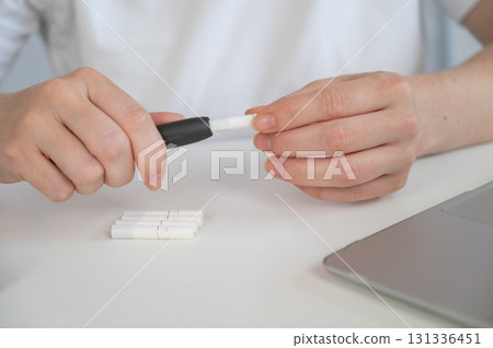 A woman inserts a cigarette stick into a tobacco heating system. Electronic cigarette. A woman inserts a cigarette stick into a tobacco heating system. Electronic cigarette. 131336451