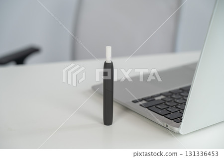 Tobacco heating system next to a laptop. Tobacco heating system next to a laptop. 131336453