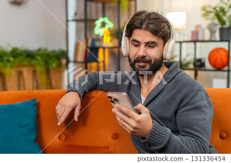 Indian man with wireless headphones listens playlist dances positive mood chill music session vibe Indian man with wireless headphones listens playlist dances positive mood chill music session vibe 131336454