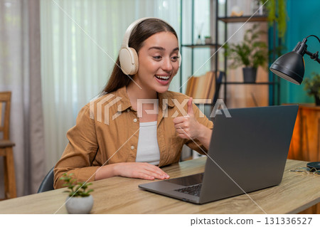 Young woman on laptop video call wearing wireless headset speaking live providing customer support 131336527