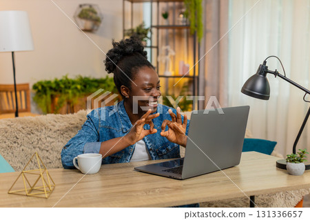African American woman waving hand while chatting with friends conversation online on laptop at home 131336657