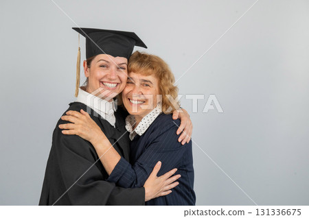 Portrait of Caucasian woman in graduation gown with her mother. Portrait of Caucasian woman in graduation gown with her mother. 131336675
