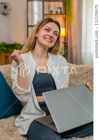 Adult woman closing laptop at home with satisfaction, celebrating task work completion with joy 131336676