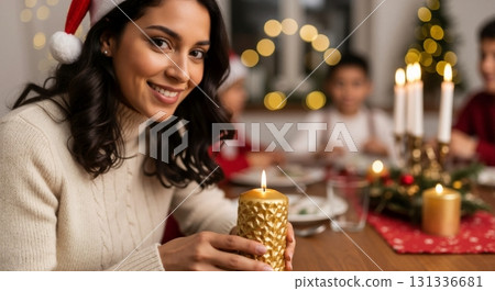 Smiling woman in a Santa hat holding a candle during Christmas dinner. Happy family celebrating the holidays at home. Festive winter season tradition Smiling woman in a Santa hat holding a candle during Christmas dinner. Happy family celebrating the holidays at home. Festive winter season tradition 131336681
