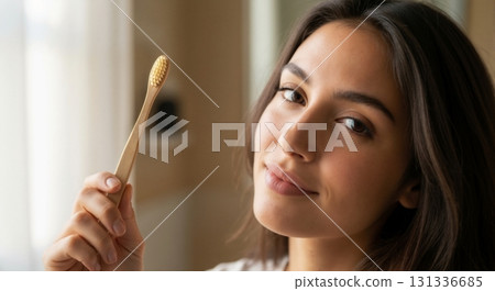 Happy woman holding a natural bamboo toothbrush. Close-up portrait promoting sustainable dental care. Eco-friendly and zero waste lifestyle concept 131336685