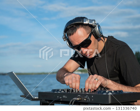 Male DJ playing music on the beach.  131336740