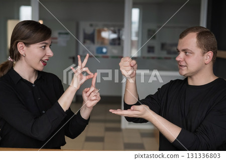 A man and a woman are talking in Russian sign language.  131336803