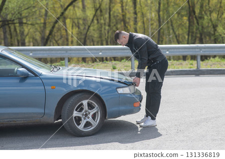 Caucasian man looking under the hood of his car.  131336819