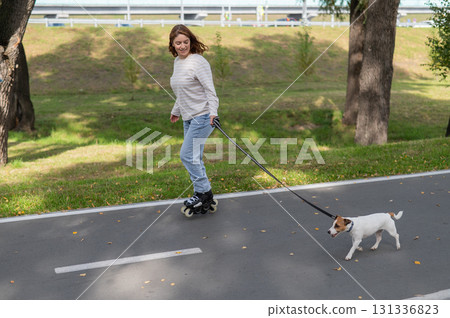 Caucasian woman roller skating with her jack russell terrier dog in park.  131336823