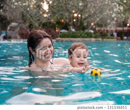 Caucasian woman holds her son while swimming in a pool on vacation. Mom teaches little boy to swim. Caucasian woman holds her son while swimming in a pool on vacation. Mom teaches little boy to swim. 131336851