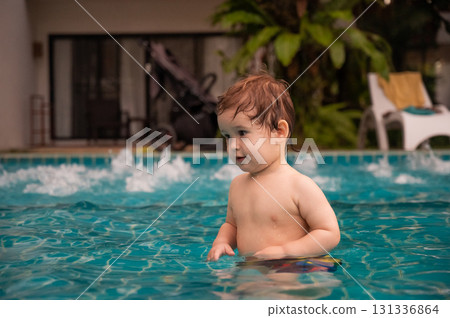 Caucasian one year old boy playing ball in swimming pool. Caucasian one year old boy playing ball in swimming pool. 131336864