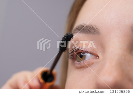 Young Woman Applying Mascara to Enhance Eyelashes. Young Woman Applying Mascara to Enhance Eyelashes. 131336896