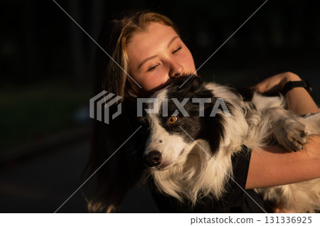 Young Caucasian woman hugging her border collie dog while walking in the park.  131336925