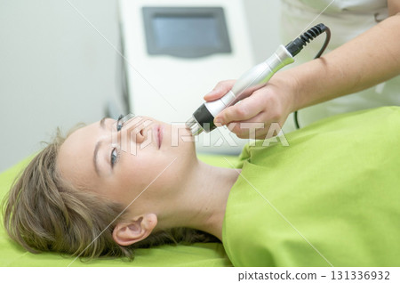 Caucasian woman undergoing radio wave RF lifting procedure in beauty salon. Caucasian woman undergoing radio wave RF lifting procedure in beauty salon. 131336932