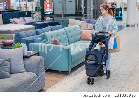 A Caucasian woman is shopping with her Jack Russell Terrier dog in a stroller in a shopping mall. A Caucasian woman is shopping with her Jack Russell Terrier dog in a stroller in a shopping mall. 131336986