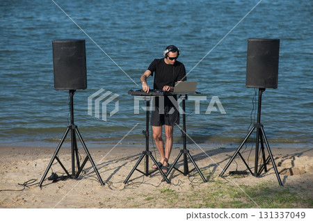 Caucasian man works as a DJ on the beach. Caucasian man works as a DJ on the beach. 131337049