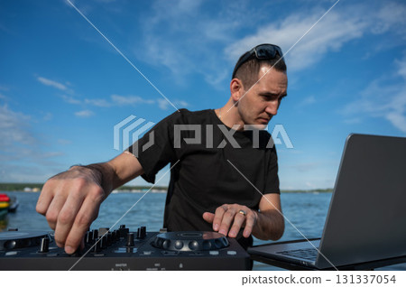 Caucasian man works as a DJ on the beach. Caucasian man works as a DJ on the beach. 131337054