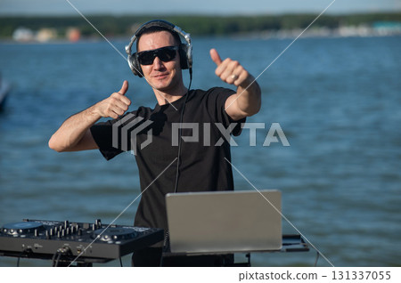 Caucasian man works as a DJ on the beach.  131337055