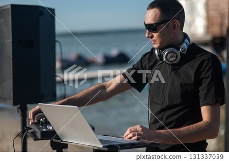 Caucasian man works as a DJ on the beach. Caucasian man works as a DJ on the beach. 131337059