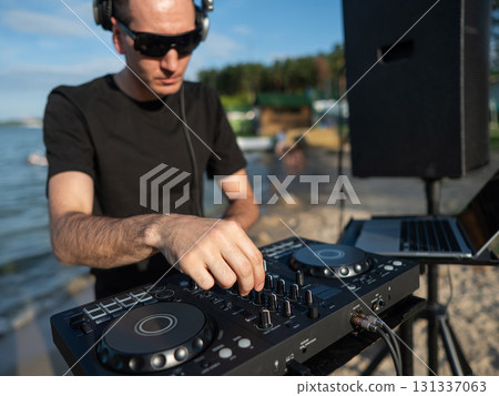 Caucasian man works as a DJ on the beach.  131337063