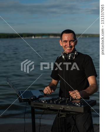 Caucasian man works as a DJ on the beach.  131337065