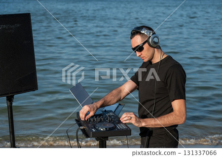 Caucasian man works as a DJ on the beach. Caucasian man works as a DJ on the beach. 131337066