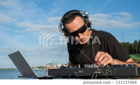 Caucasian man works as a DJ on the beach. Caucasian man works as a DJ on the beach. 131337068